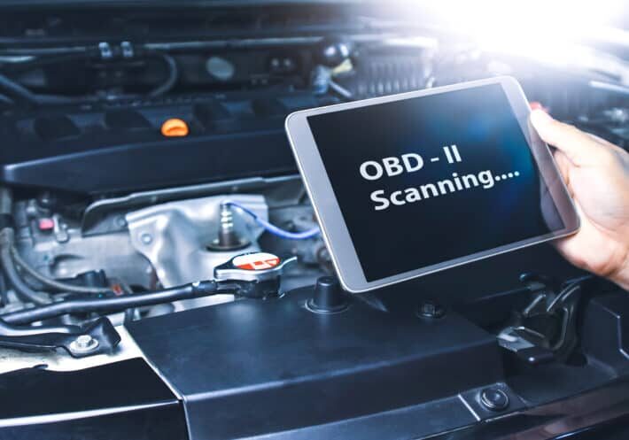 Technician diagnostics of code failure with OBD2 scanner technol Technician diagnostics of code failure with OBD2 scanner technology on tablet in the auto repair garage